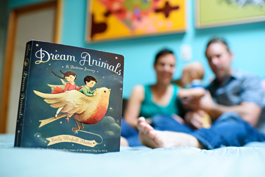 A couple reading to their baby in the bed.